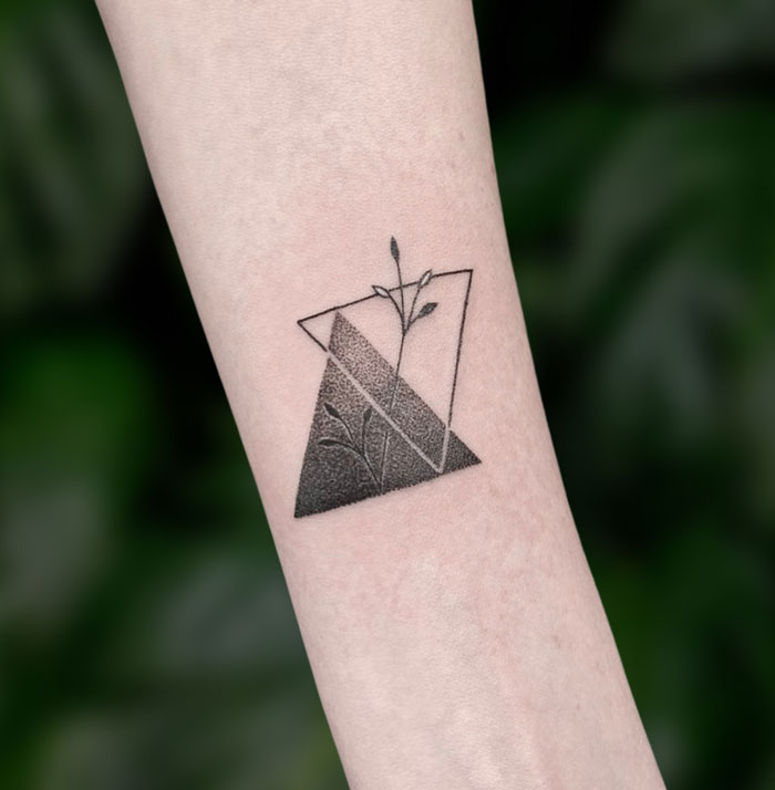 Geometric tattoo design featuring overlapping triangles and plant elements.