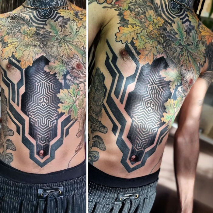 Chest adorned with geometric tattoo featuring intricate black lines and colorful leaves.