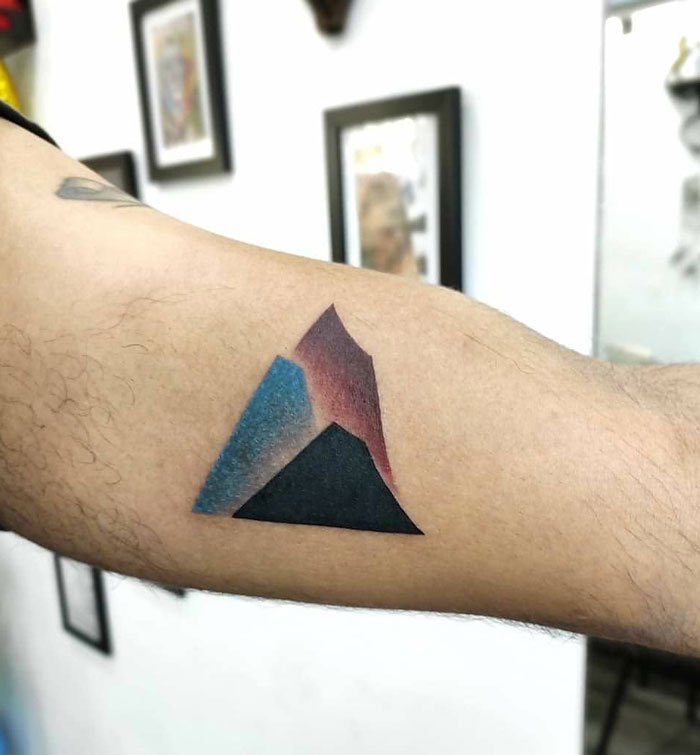 Geometric tattoo of a colorful triangular shape on a person's arm.