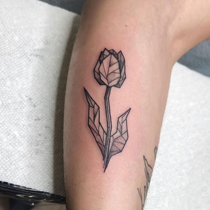 Geometric tattoo of a stylized tulip with angular lines on a person's arm.