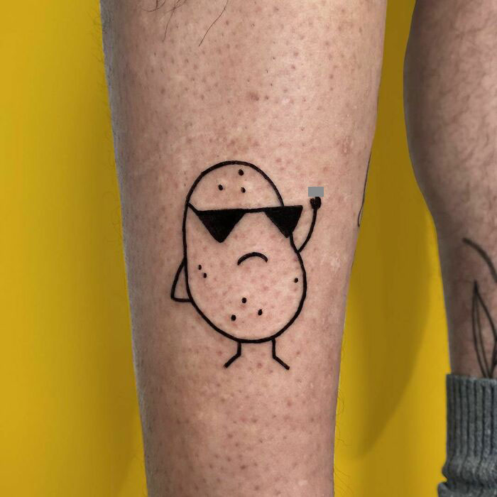 Funny tattoo of a potato with sunglasses on a leg, with a yellow background.