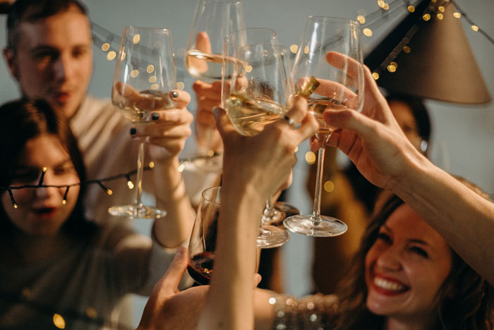 People toasting white wine glasses and laughing