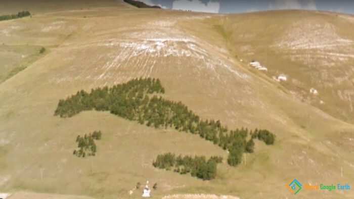 Aerial view of a hillside shaped like a dinosaur captured in an amusing and ridiculous moment on Google Maps.