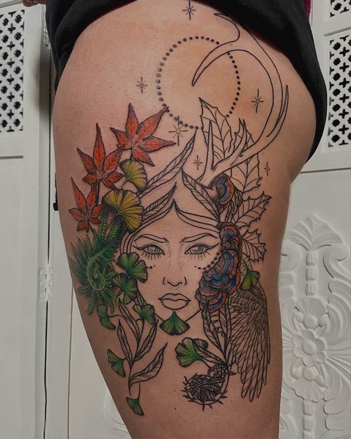 Detailed nature tattoo with flowers and celestial elements celebrating the human-earth bond on a person's thigh.