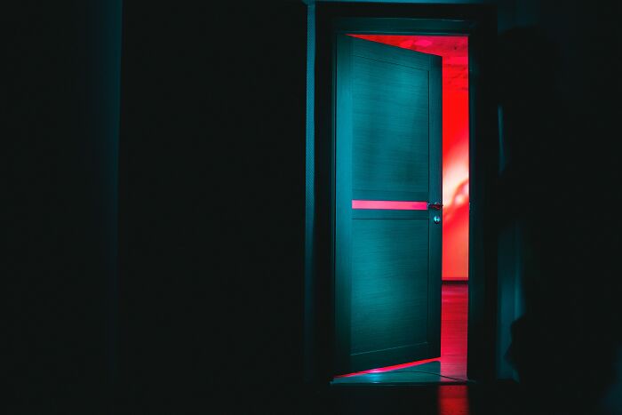 Dimly lit open door with neon lighting, creating a mysterious atmosphere fitting for juicy gossip revelations.