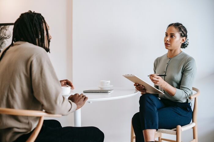 Woman Listening And Taking Notes Of What Man Says 