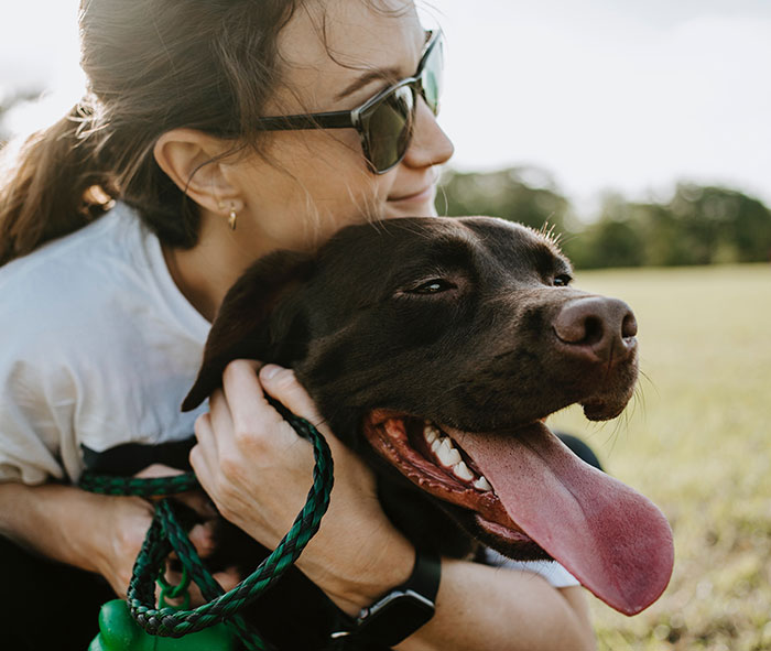 Person hugging black dog