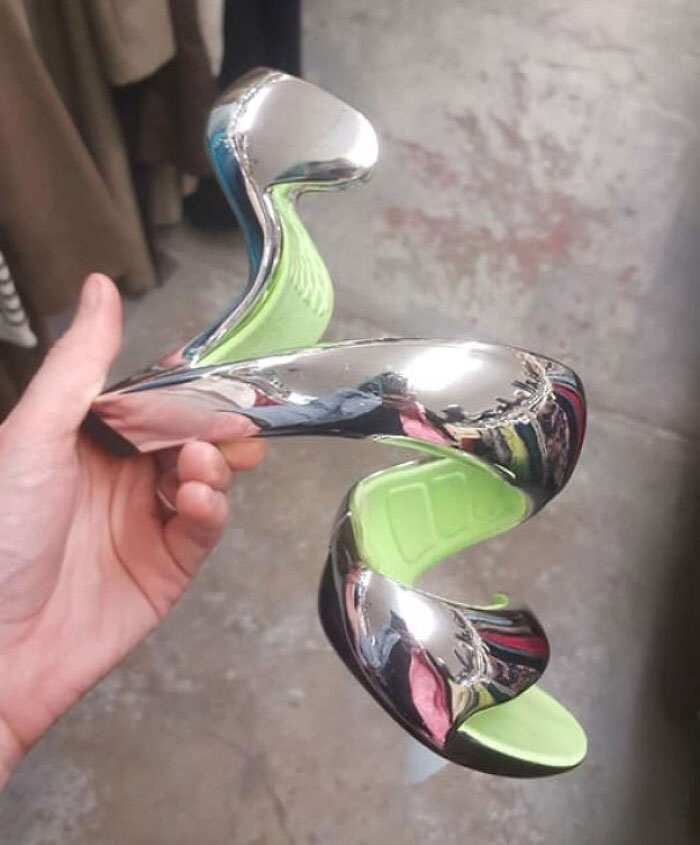 Unusual chrome and green shoe with a spiral design being held in hand.