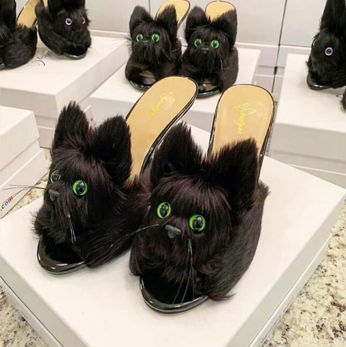 Weird shoes designed like fluffy black cats with green eyes on display.