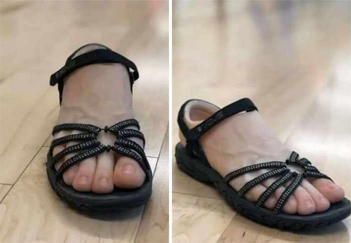 Weird shoes designed to look like feet, featuring black straps and a sandal style on a wooden floor.