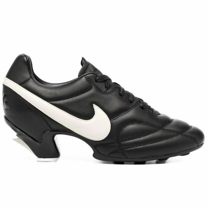Unusual black high-heeled shoe with a white swoosh logo, combining athletic and formal styles in a weird design.