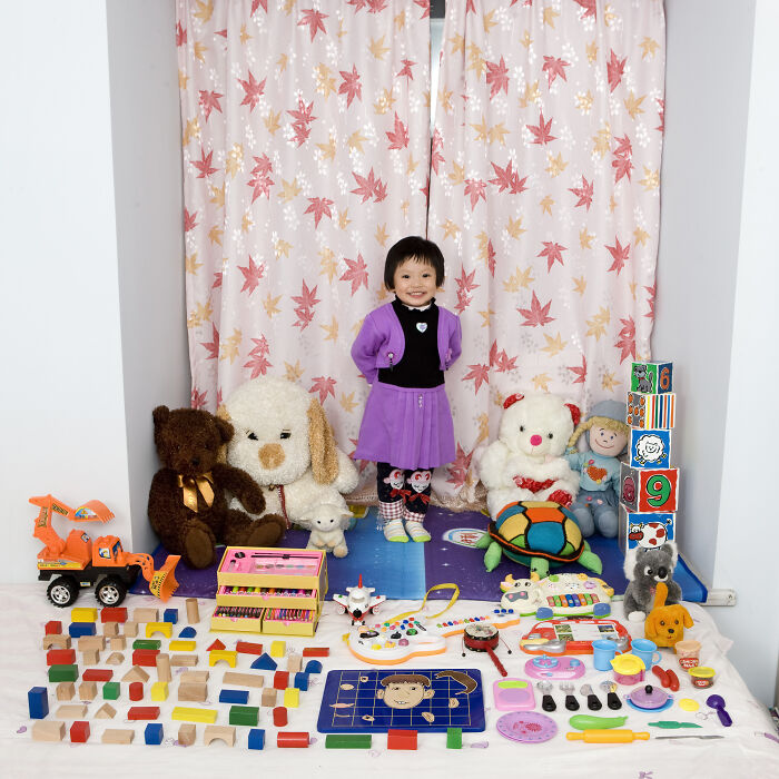 Young child standing with a colorful toy collection showcasing toys and stuffed animals from the series Toy Stories.