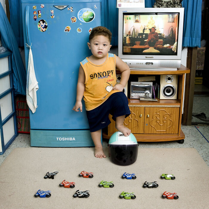 Young child posing with a collection of toy motorcycles at home, showcasing global toy collections in the Toy Stories series.