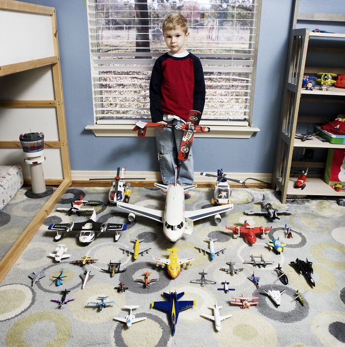 Young boy showcasing extensive toy airplane collection in his room for the series focusing on children’s toy collections worldwide
