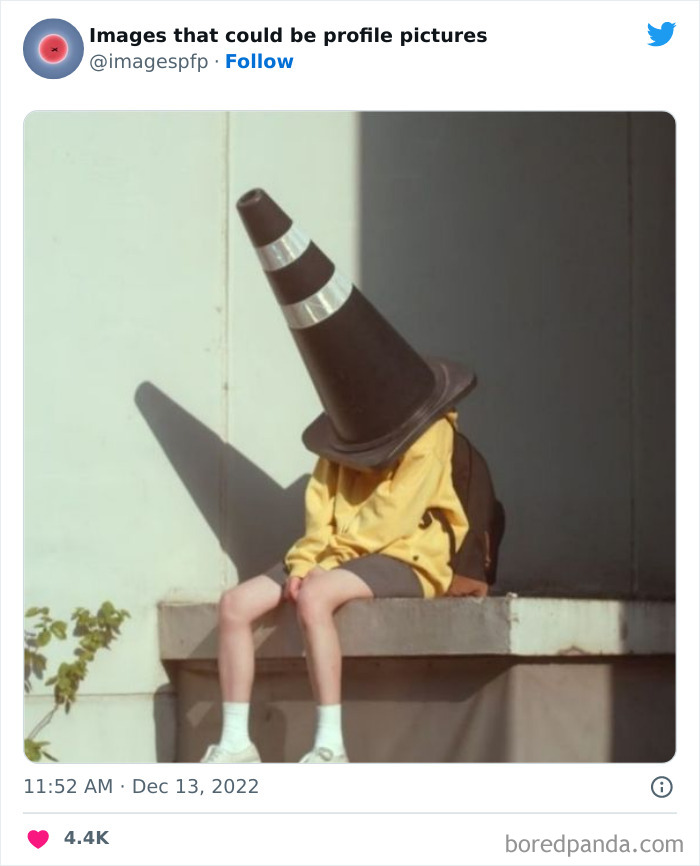 Child wearing oversized traffic cone on head, sitting on ledge in a weird and funny profile picture moment.