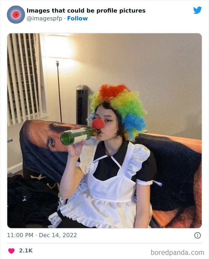 Person wearing a colorful clown wig and red nose drinking from a bottle, featured in weird and funny profile pictures.