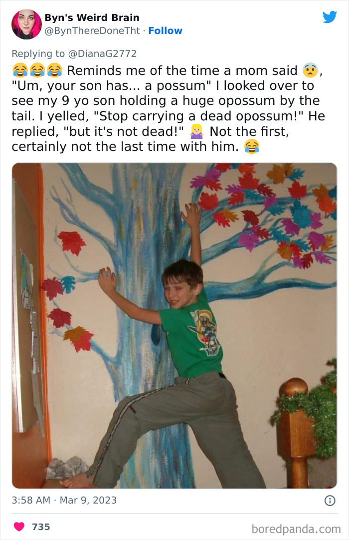 Young boy striking a playful pose climbing a painted tree indoors, showcasing kids doing something unhinged and surprising.