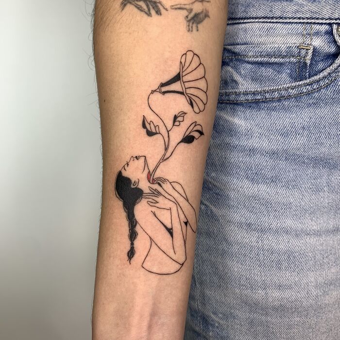 Illustrative tattoo of a woman with floral elements on an arm, resembling artwork.