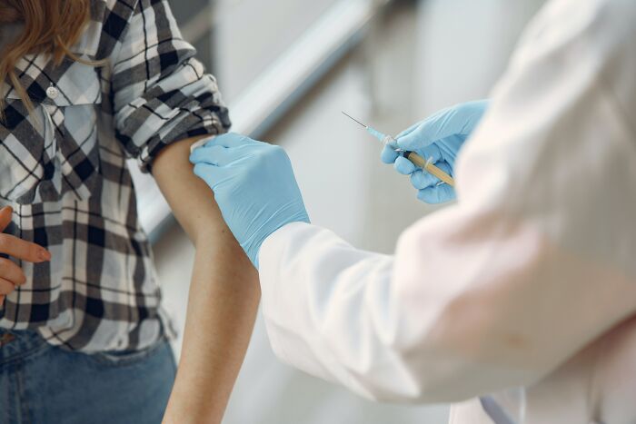 Healthcare worker administering a vaccine to a patient in a checkered shirt, correcting myths about vaccinations.