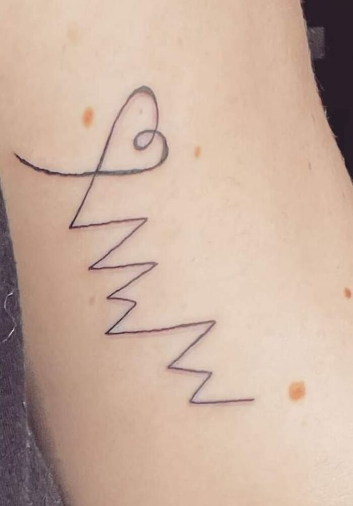 Amusingly bad tattoo with simple lines and curves on skin, showcasing inkshaming humor.
