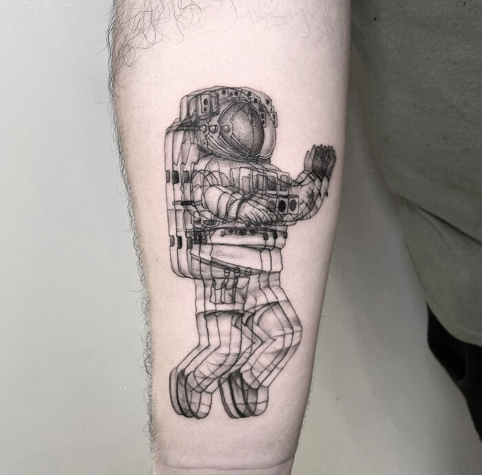 Forearm tattoo of a moving astronaut in detailed, layered style, creating a dizzying effect.
