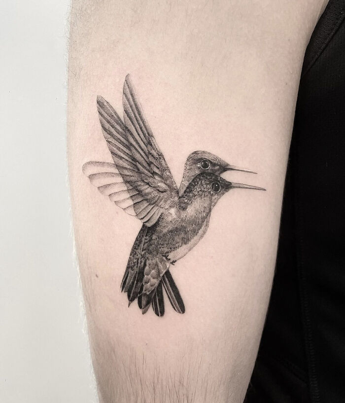 Hummingbird tattoo on arm, designed to appear "moving" with two heads and wing positions creating a dizzying effect.