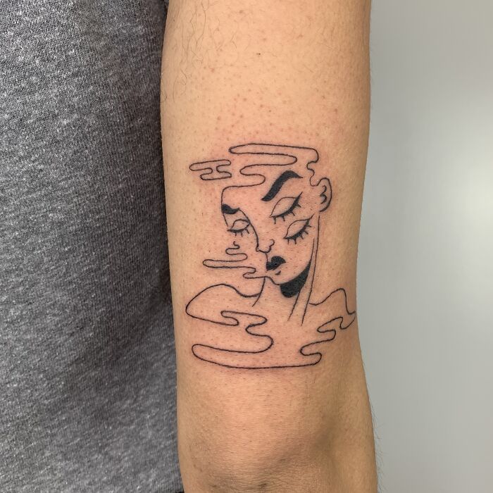 Tattoo illustration on forearm depicting a serene face mingled with abstract line elements.