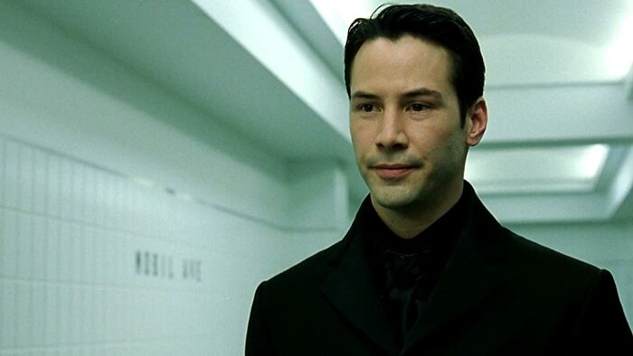Actor in a dark suit in a modern corridor, representing one of the highest-paid actors of all time.