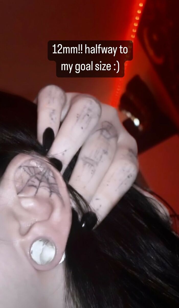 Stretched earlobe with a spider web tattoo, possibly a permanent mistake, and hand with finger tattoos.