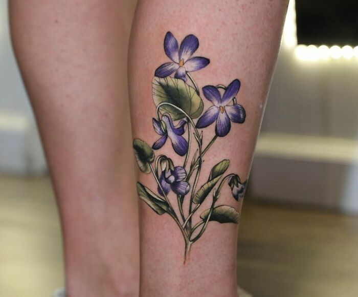 Beautiful watercolor tattoo of purple flowers on a leg, showcasing inkspiration.