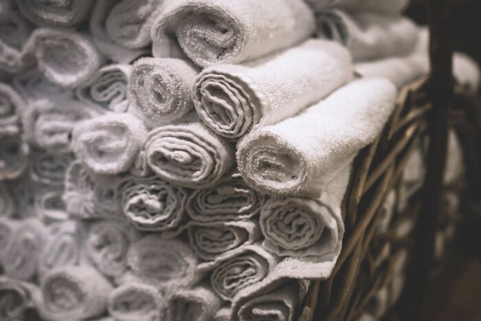 Rolled white towels neatly stacked in a wicker basket, showcasing efficient home organization ideas.