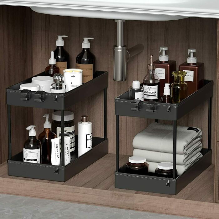 Under-sink home organization idea with shelves holding bottles and neatly folded towels.