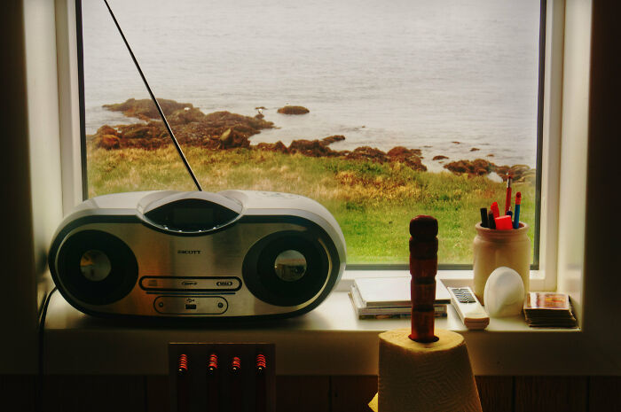 Home organization idea with a tidy windowsill featuring a stereo, books, and pens overlooking a scenic landscape.