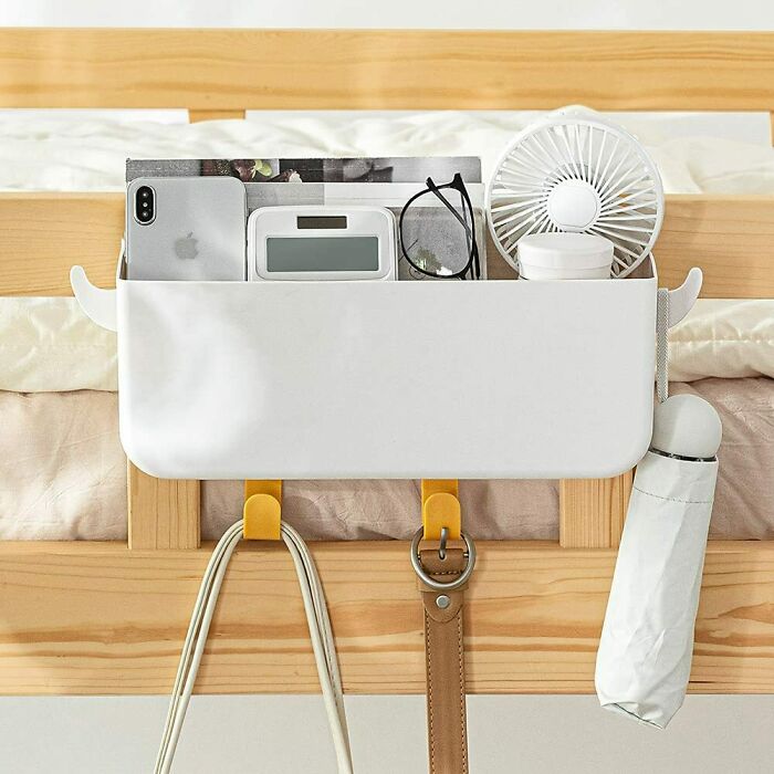 Bedside storage organizer with pockets holding a phone, fan, and glasses for efficient home organization.