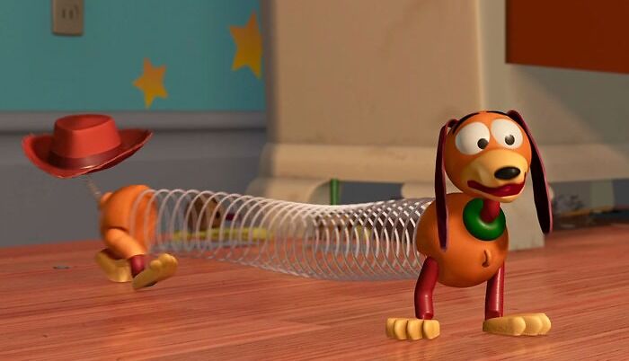 Slinky Dog from Toy Story, a famous cartoon dog with a stretchable spring body, standing on a wooden floor.