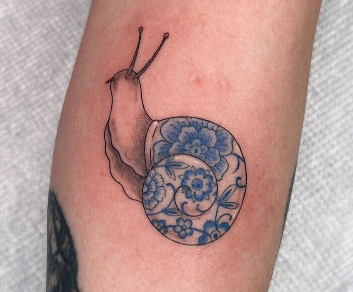Snail tattoo with a floral shell design on skin, showcasing creative animal tattoos.