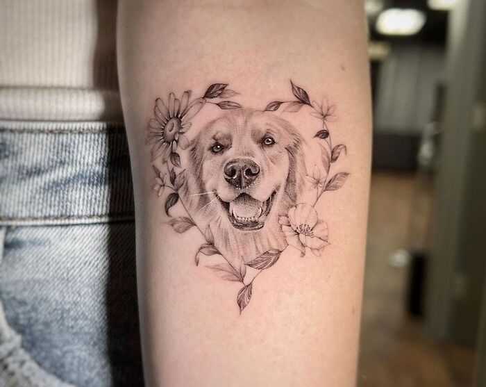 Animal tattoo of a dog's face surrounded by flowers on a person's arm.