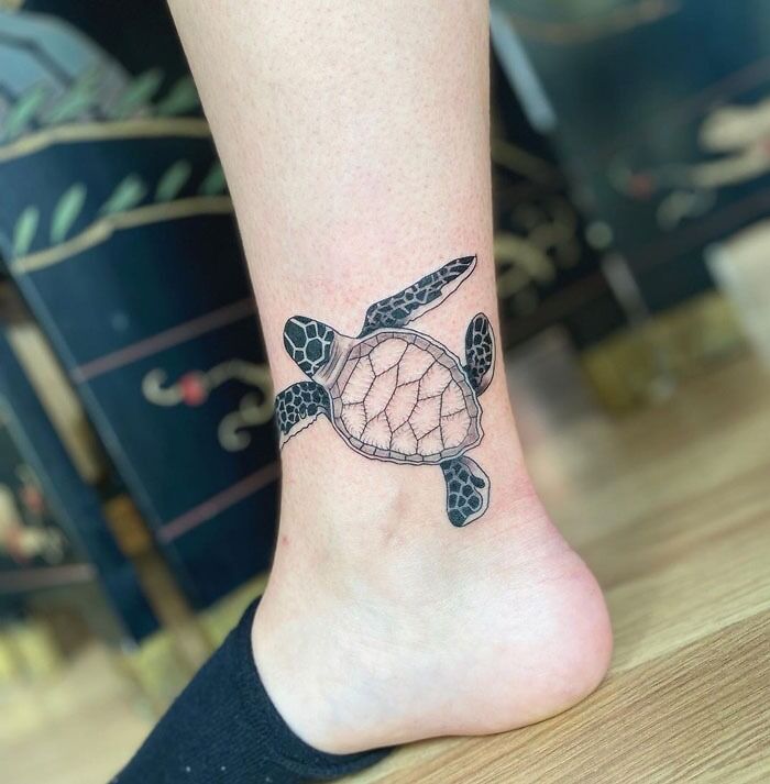 Turtle tattoo on ankle showcasing intricate animal design.