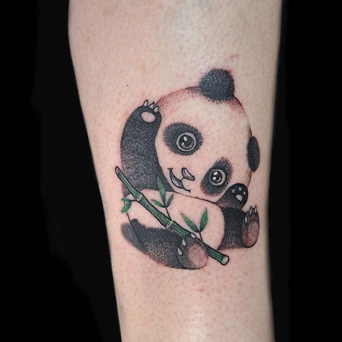Cute panda tattoo holding bamboo on forearm, creative animal tattoo design idea.