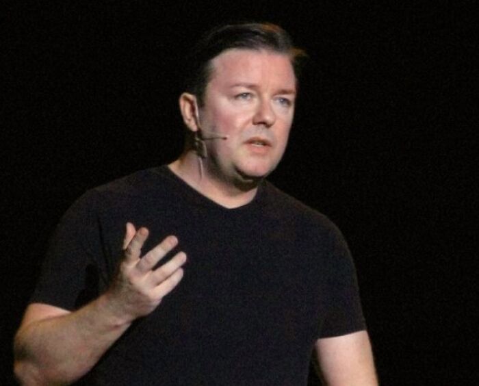 Ricky Gervais wearing a black sweater, speaking on stage, featured in celebrities who never married yet found love.