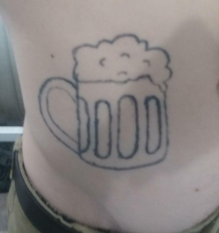 Funny tattoo of a beer mug with frothy top on someone's stomach.