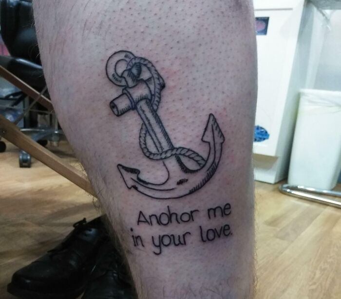 Funny tattoo of an anchor with text saying "Anhor me in your love" on a person's leg.