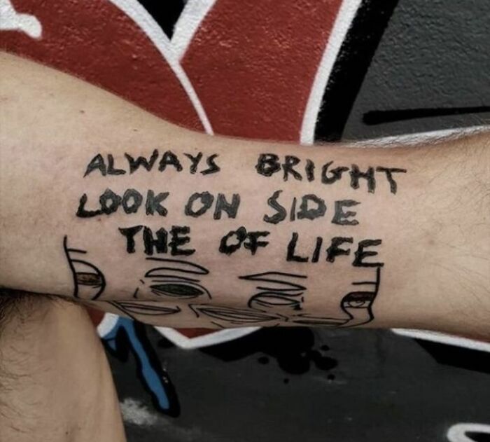 Funny tattoo with jumbled text saying, "Always look on the bright side of life," on an arm with a colorful background.
