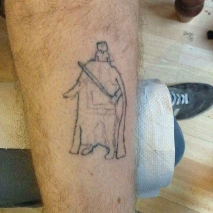 Funny tattoo on a leg depicting a simplistic outline of a character with a cape and sword.