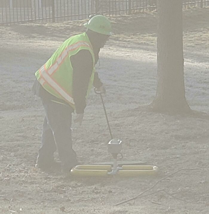 Construction Device With A Yellow Base. Not Sure If It Goes Into The Ground. Makes Melodic Humming Noises At Regular Intervals And Increases In Pitch