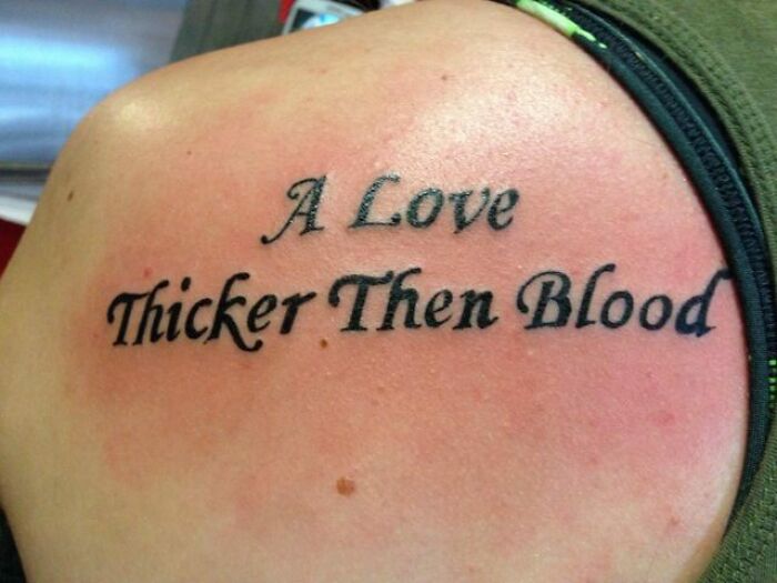 Funny tattoo with a text typo: "A Love Thicker Then Blood" on a person's back.