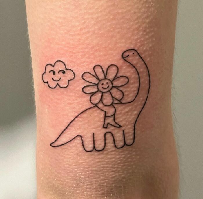 Funny tattoo of a smiling dinosaur with a happy flower and cloud.
