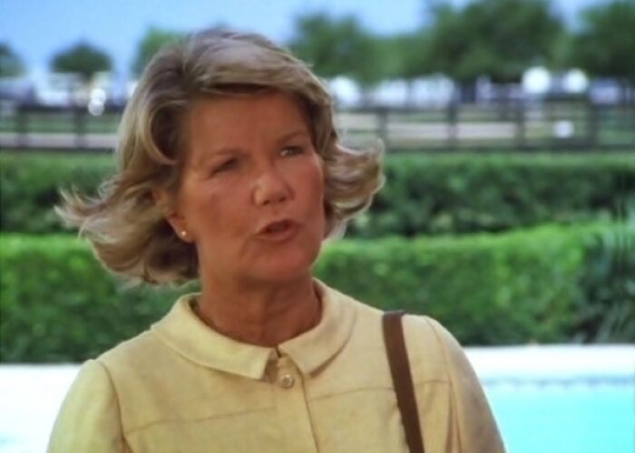 Ellie Ewing in a yellow outfit is standing and talking