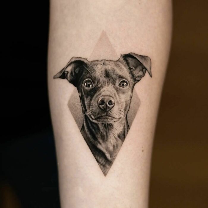 Realistic dog tattoo on forearm, highlighting flawless detail and lifelike art.