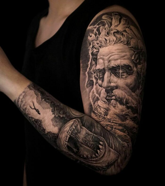 Realistic tattoo of a bearded man's face and shark on an arm, showcasing museum-worthy detail and artistry.